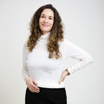 Ingvild Stjernen Tisløv Portrettbilde av kvinne med langt, krøllete hår og hvit genser.