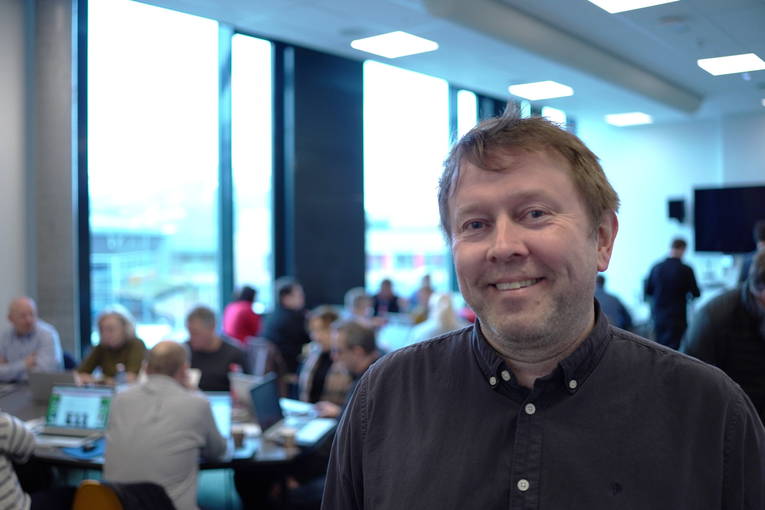 Dekan Ivar John Erdal ved Høgskulen i Volda. Mennesker som jobber på laptoper sitter i bakgrunnen.