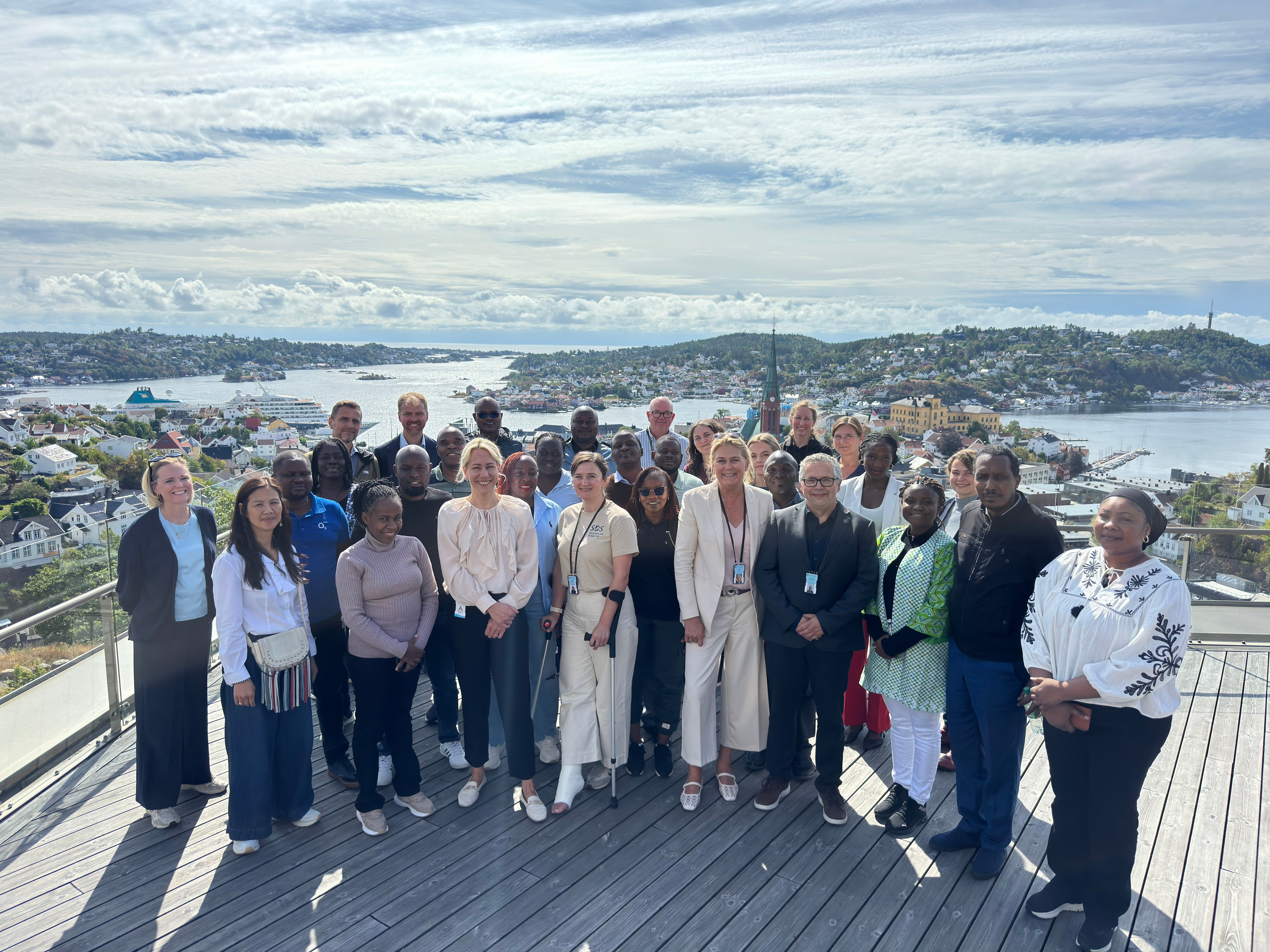Gruppebilde av deltakere fra Ghana, Kenya, Miljødirektoratet, Norad, Arendal kommune, GRID-Arendal og Statsforvalteren i Agder på utsiktsterrassen ved Statsforvalterens kontor på Fløyheia i Arendal.