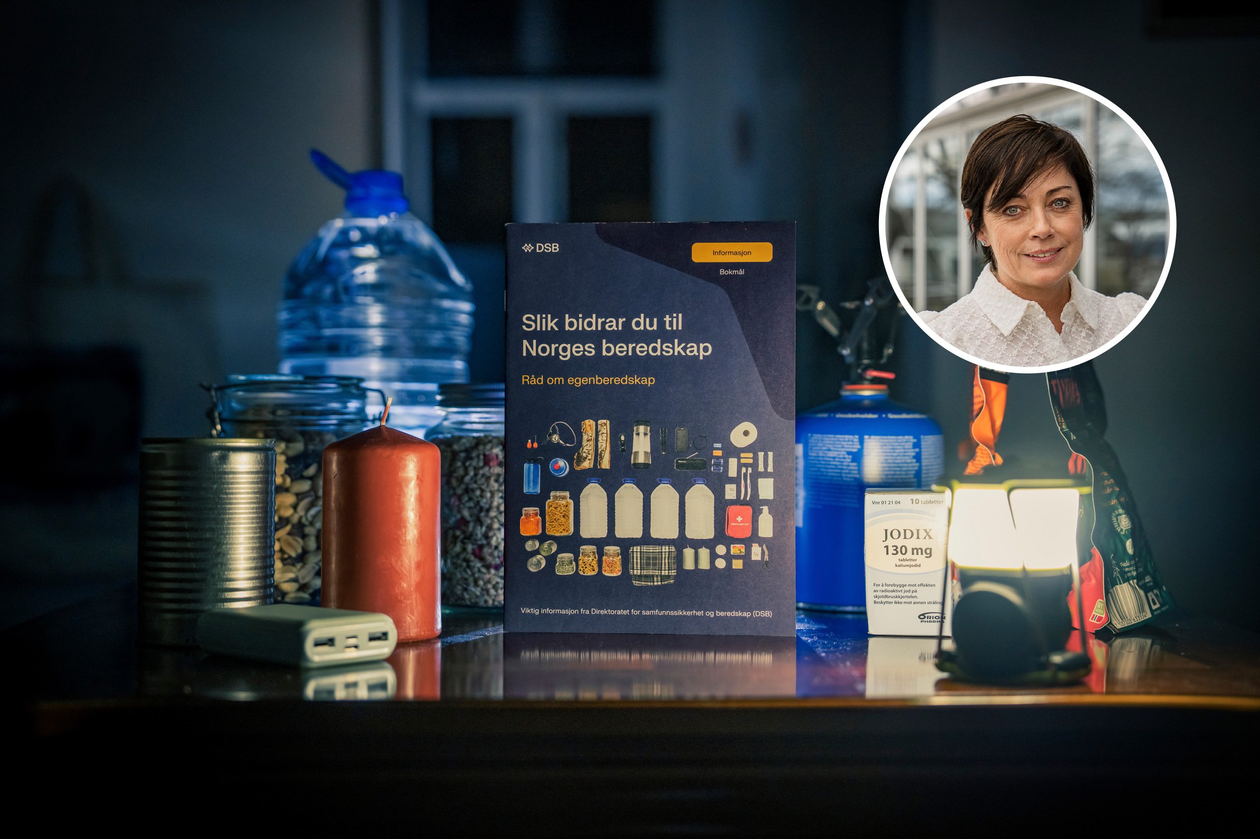 Utstyr og varer ein bør ha i eit eigenberedskapslager, som vatn, mat, lys, batteribank og kokeutstyr, samt DSB si brosjyre om eigenbredskap. Portrettbilde av statsforvaltar Else-May Botten i eit mindre bilde.