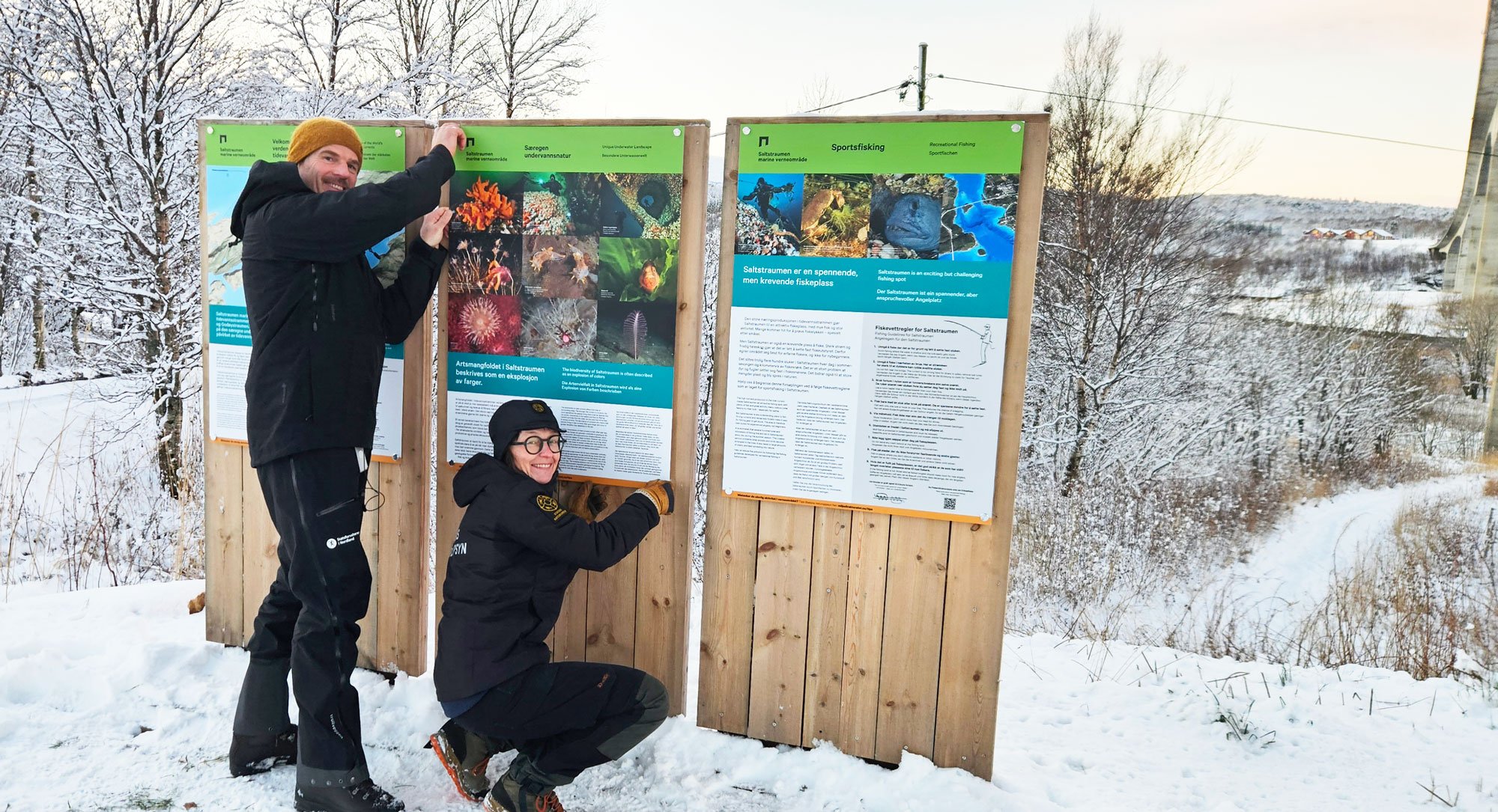 Mann og kvinne henger opp skilt. 