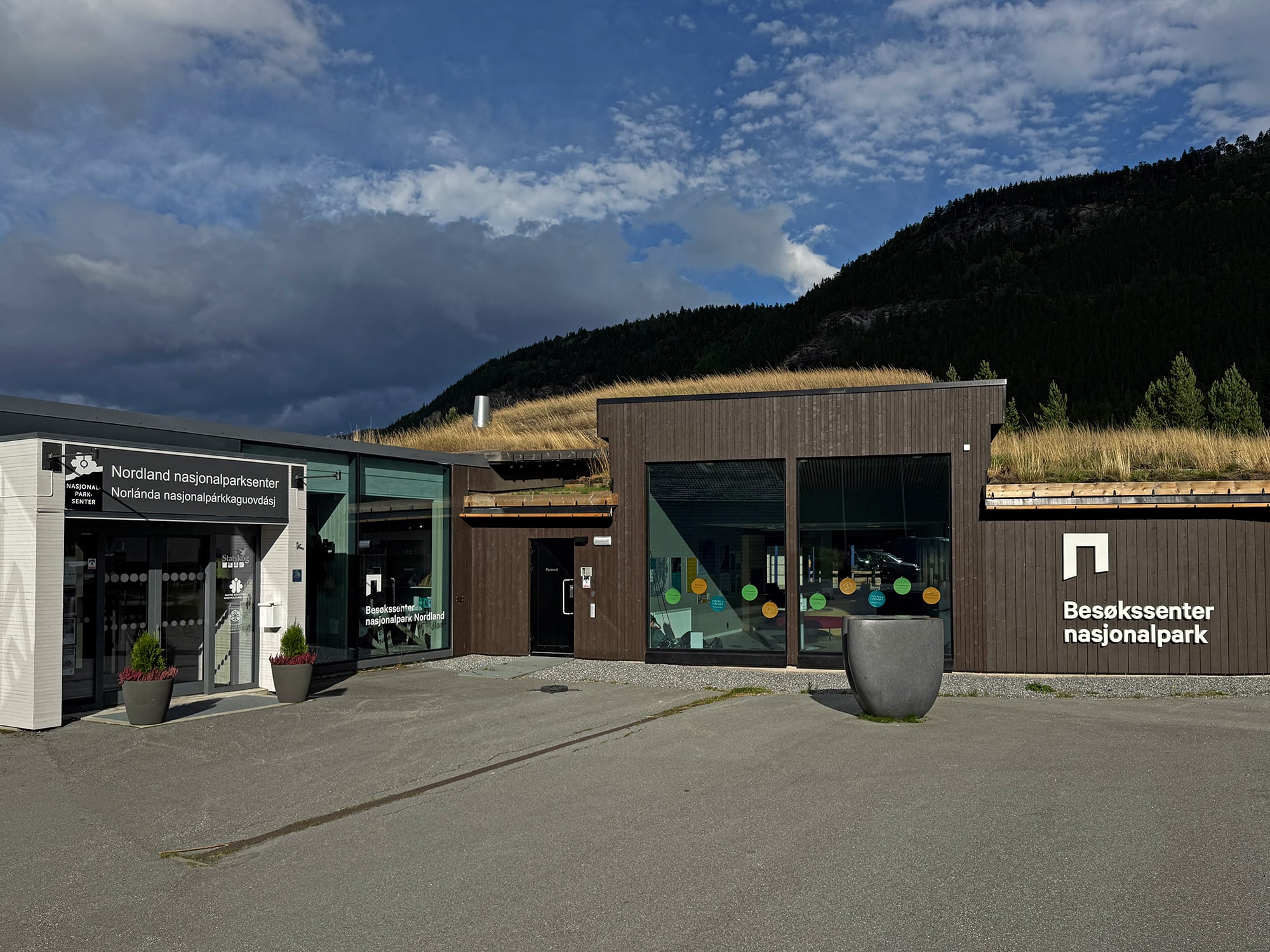 Bygning med brune og hvite vegger og gress på taket.