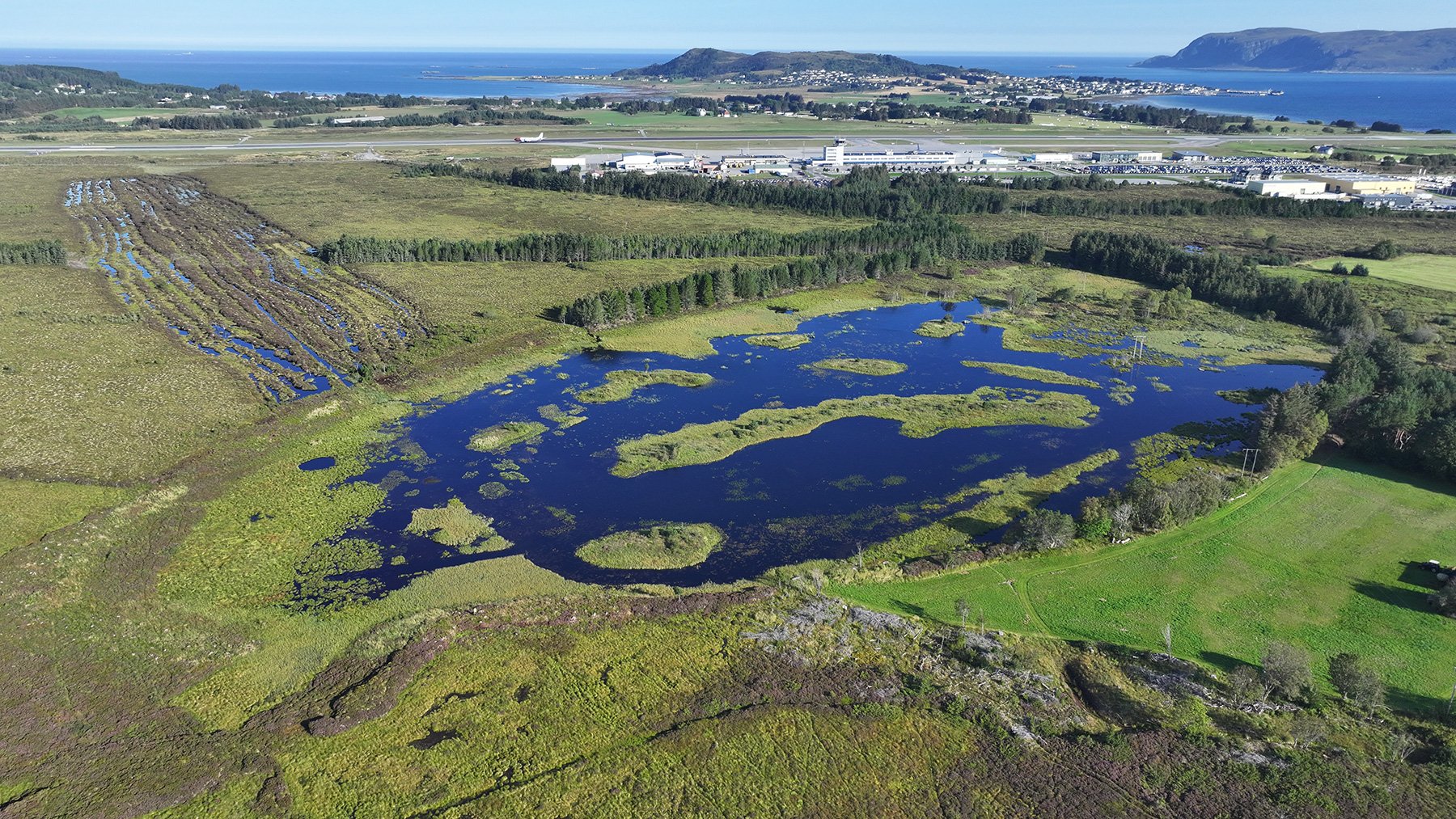 Eit bilete av eit vatn med øyar. Skog rundt vatnet.