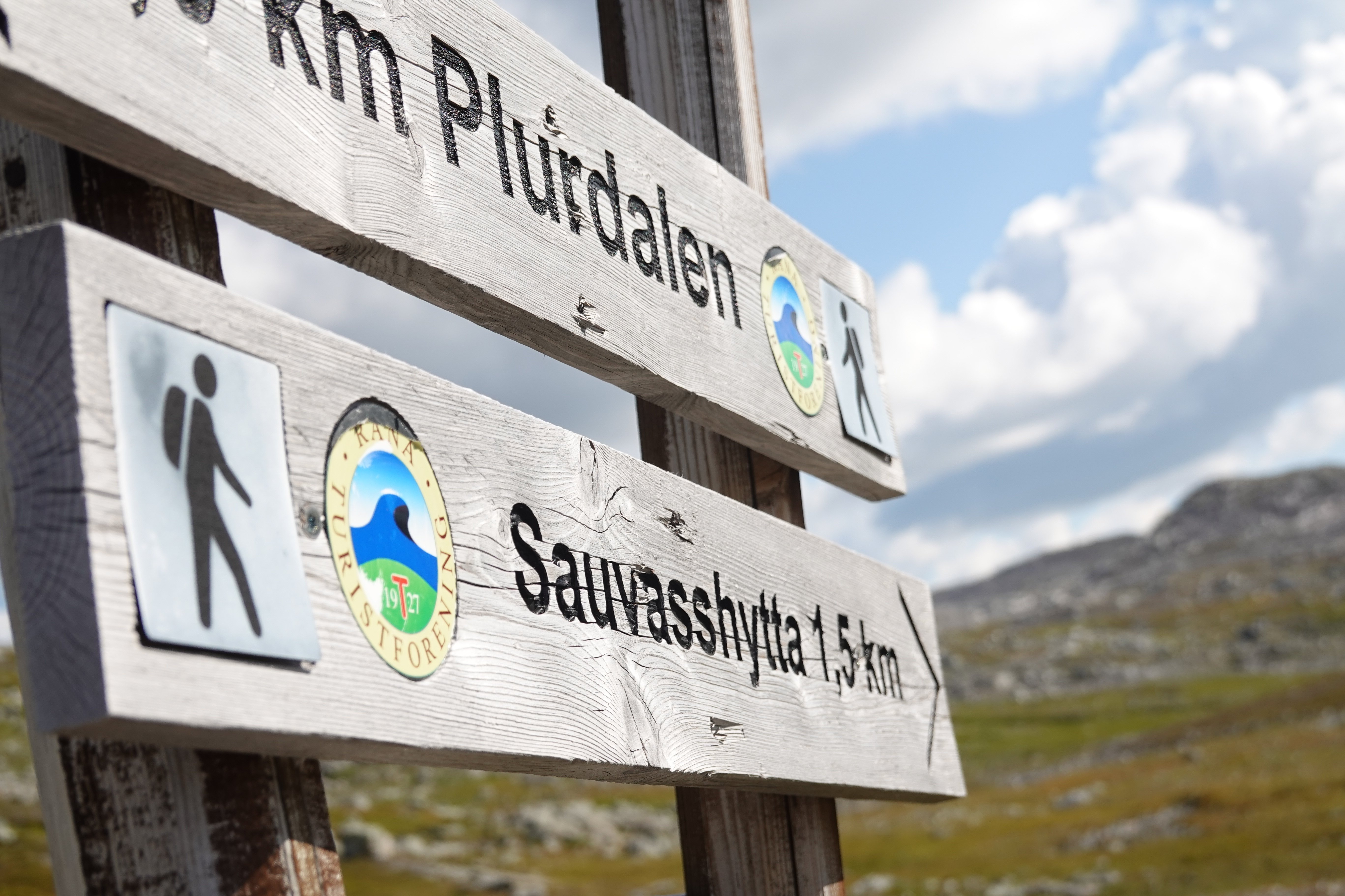 Treskilt med fjellandskap i bakgrunnen. 