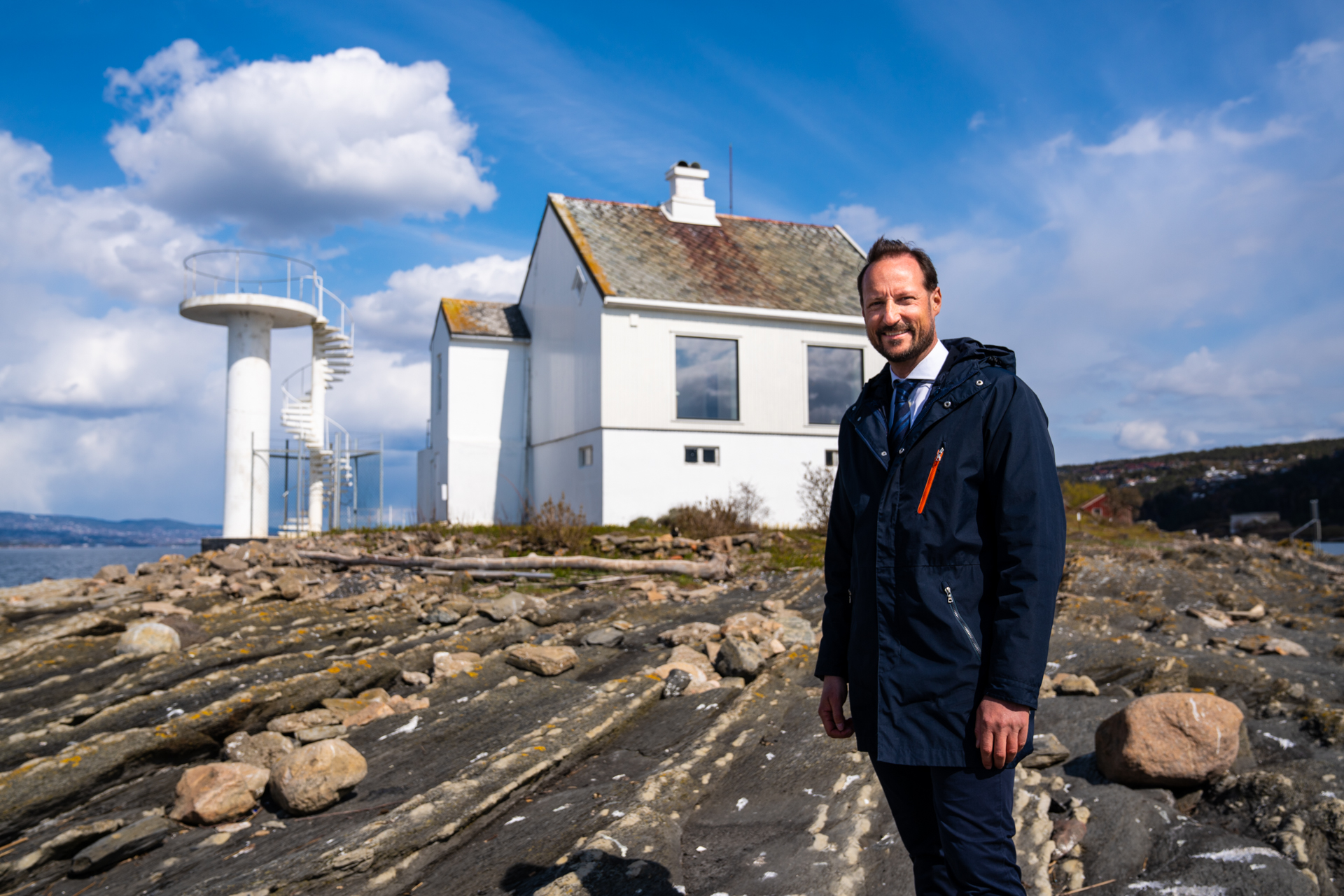 H.K.H. Kronprins Haakon ved sjøen med en fyrlykt i bakgrunnen