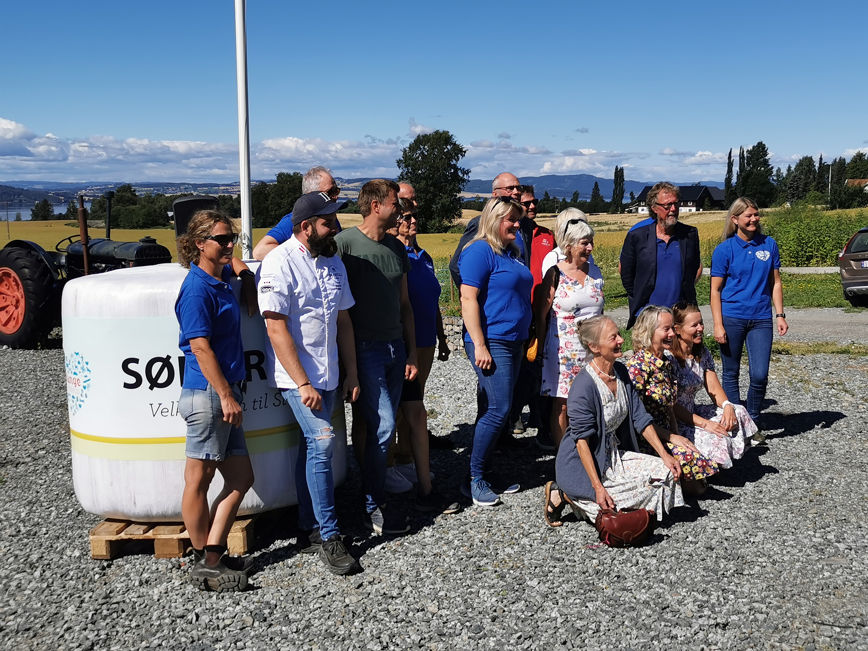 Gruppe mennesker poserer ute fremfor en rundballe