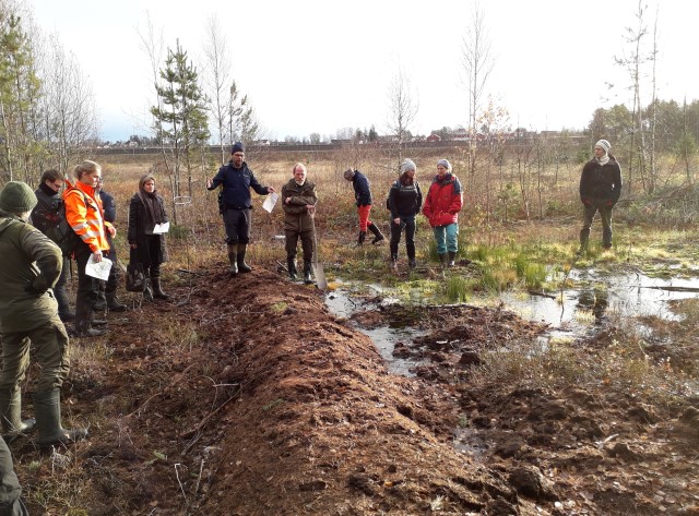 Pål Martin Eid i Statens naturoppsyn forklarer hvordan demningen fungerer til å få vannstanden i myra opp. Her på Gjennestadmyra. Foto: Fylkesmannen i Oslo og Viken