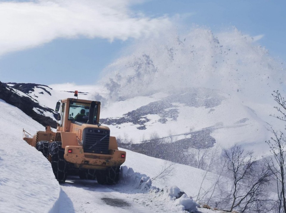 Brøytebil som brøyter ein veg på fjellet.