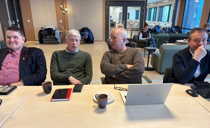 Fire menn som snakker sammen ved et bord