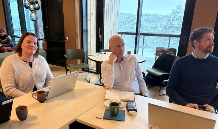 En kvinne og to menn som sitter ved et bord under et møte