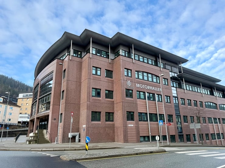 Stort kontorbygg i by, skilta med "Motorhallen" i store bokstavar på framsida.