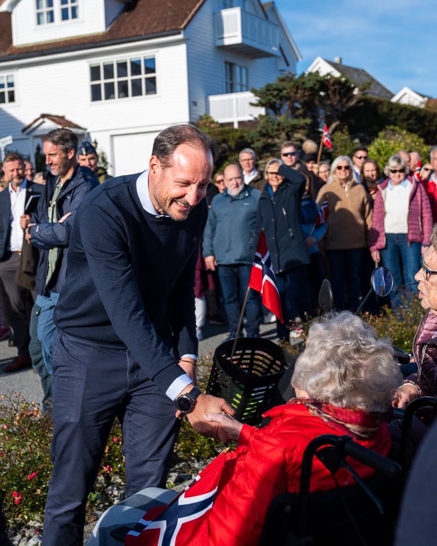 Kong Haakon hilser på eldre innbyggere under besøket på Kvitsøy.