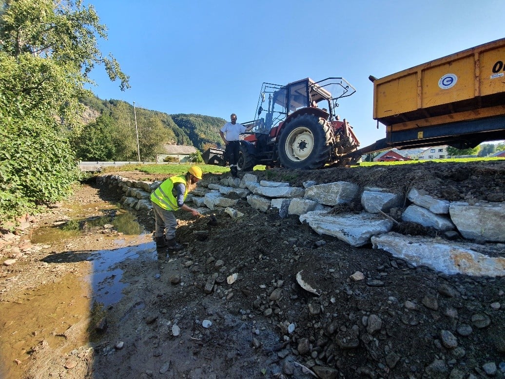 Utviding av elveløp og tilbaketrekt erosjonssikring gir meir naturvennleg tiltak enn ein rett og glatt mur. Foto: Hardangerfjord Villfisklag. Tilbaketrekt ersosjonssikring.
