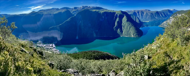 eit oversiktsbilete frå ein fjelltopp ned mot ein fjord der ein industristad ligg til venstre og ein blå fjord til høgre