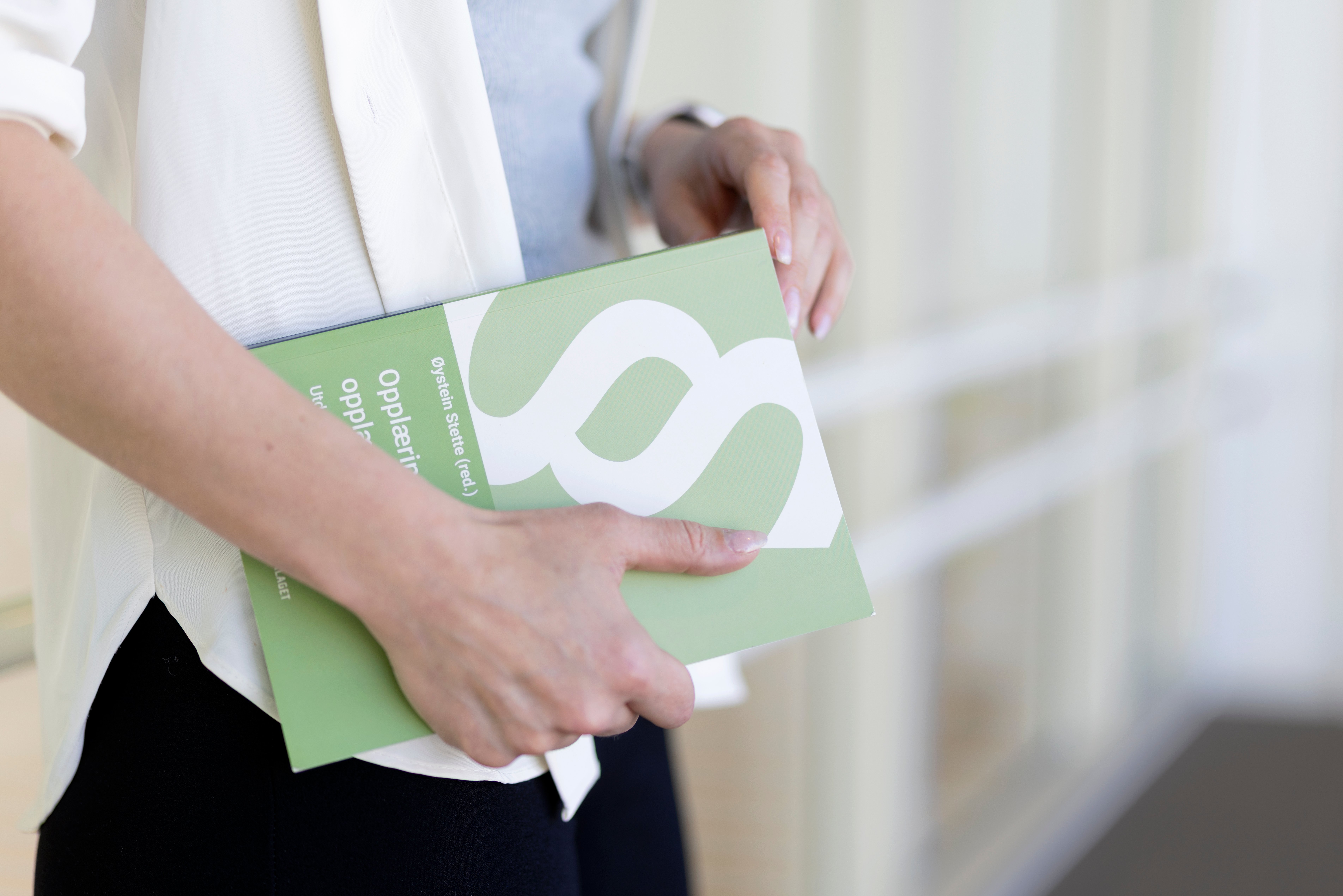 Bilde av person som holder opplæringsloven (bok) i hendene.