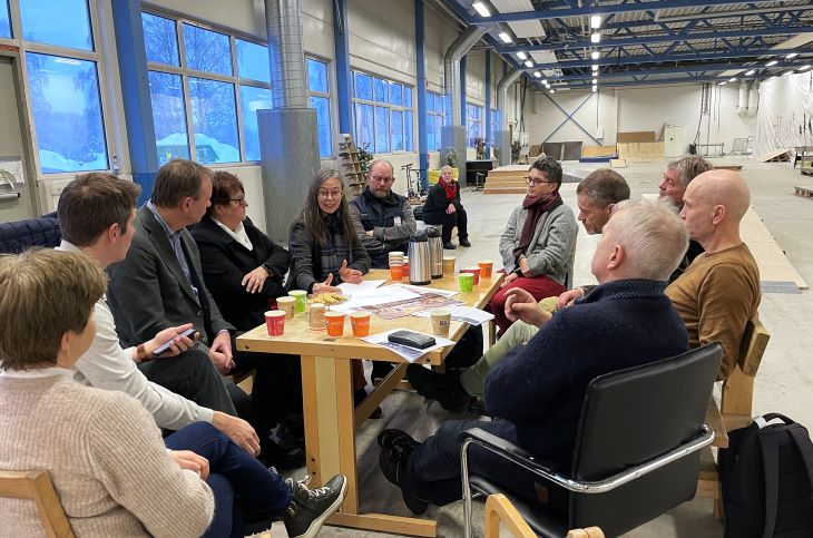 Kultursjef Caroline Rolstad forteller om planene for den nye aktivitetshallen. Foto: Benedicte Kvalsund. Folk som sitter rundt et bord og snakker