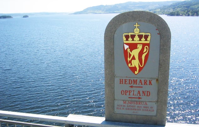 Stein med skilt som viser retning til Oppland og Hedmark