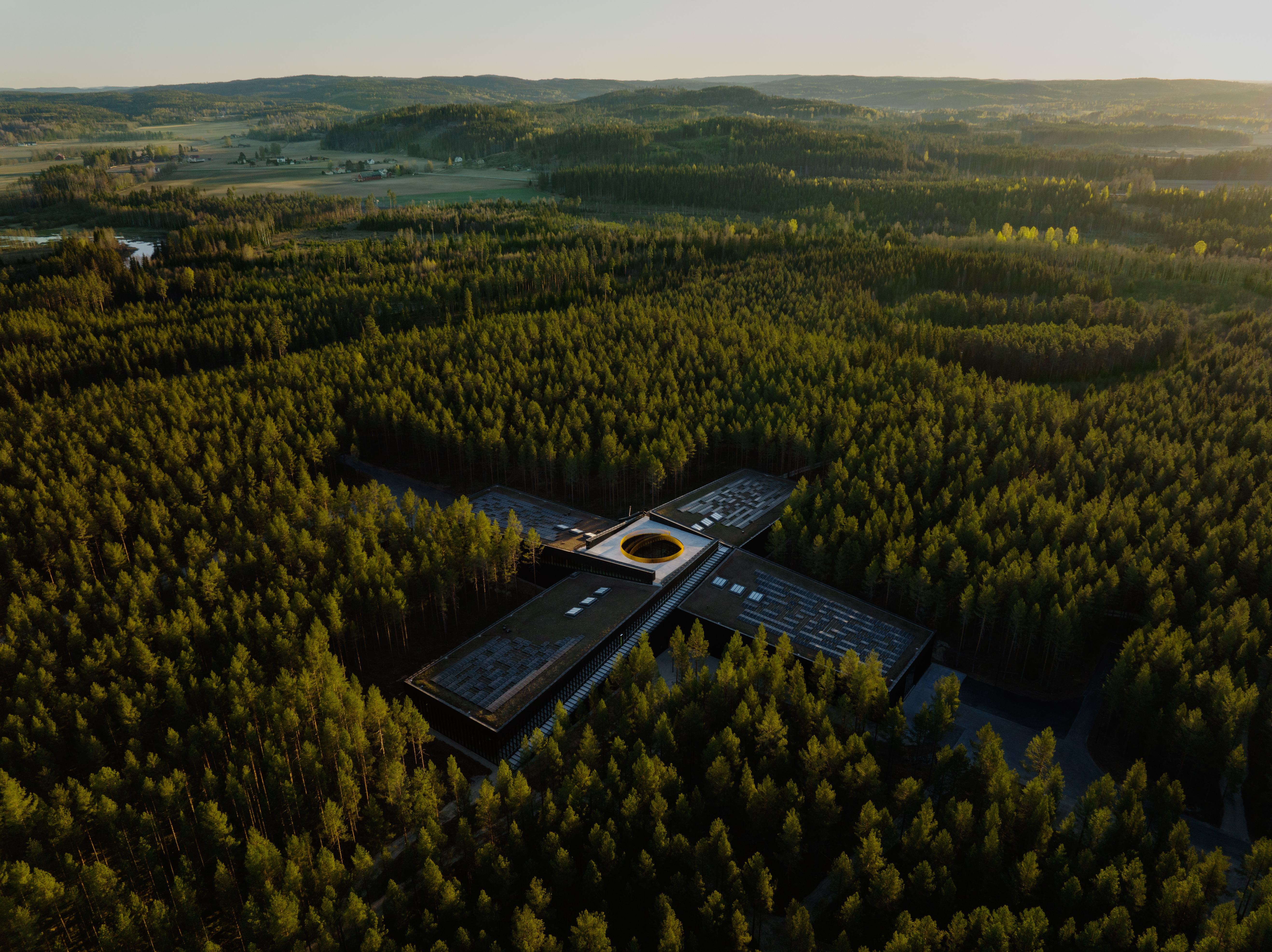 Næringsbygg formet som et plusstegn i en skog