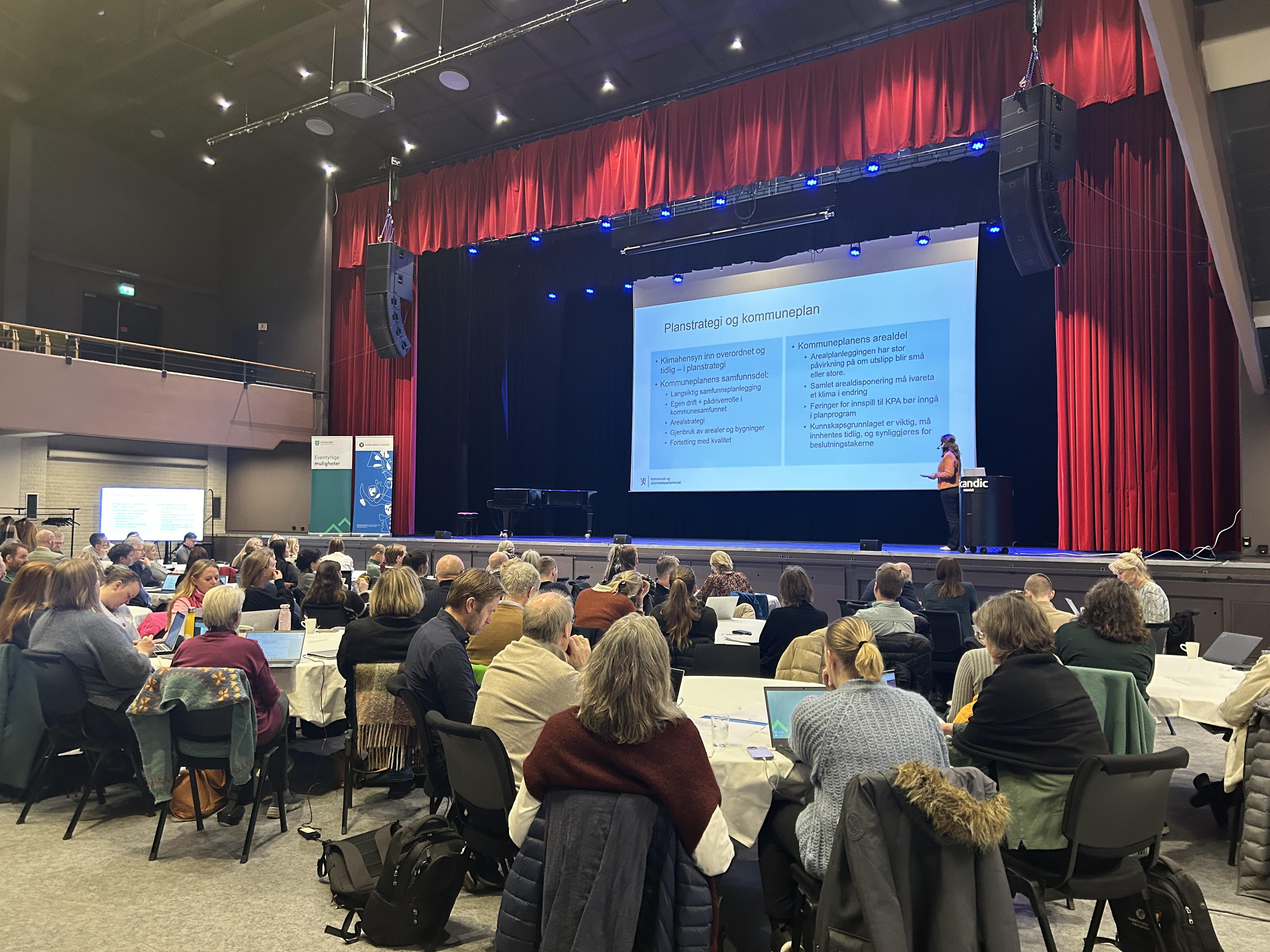 Årets natur- og klimakonferanse var fulltegnet. Her snakker Tonje Røland Brasetvik, prosjektleder i Kommunal- og distriktsdepartementet, om statlige føringer for klima og natur i planlegging.
Foto: Leila Øvreseth. Konferansesal med mennesker