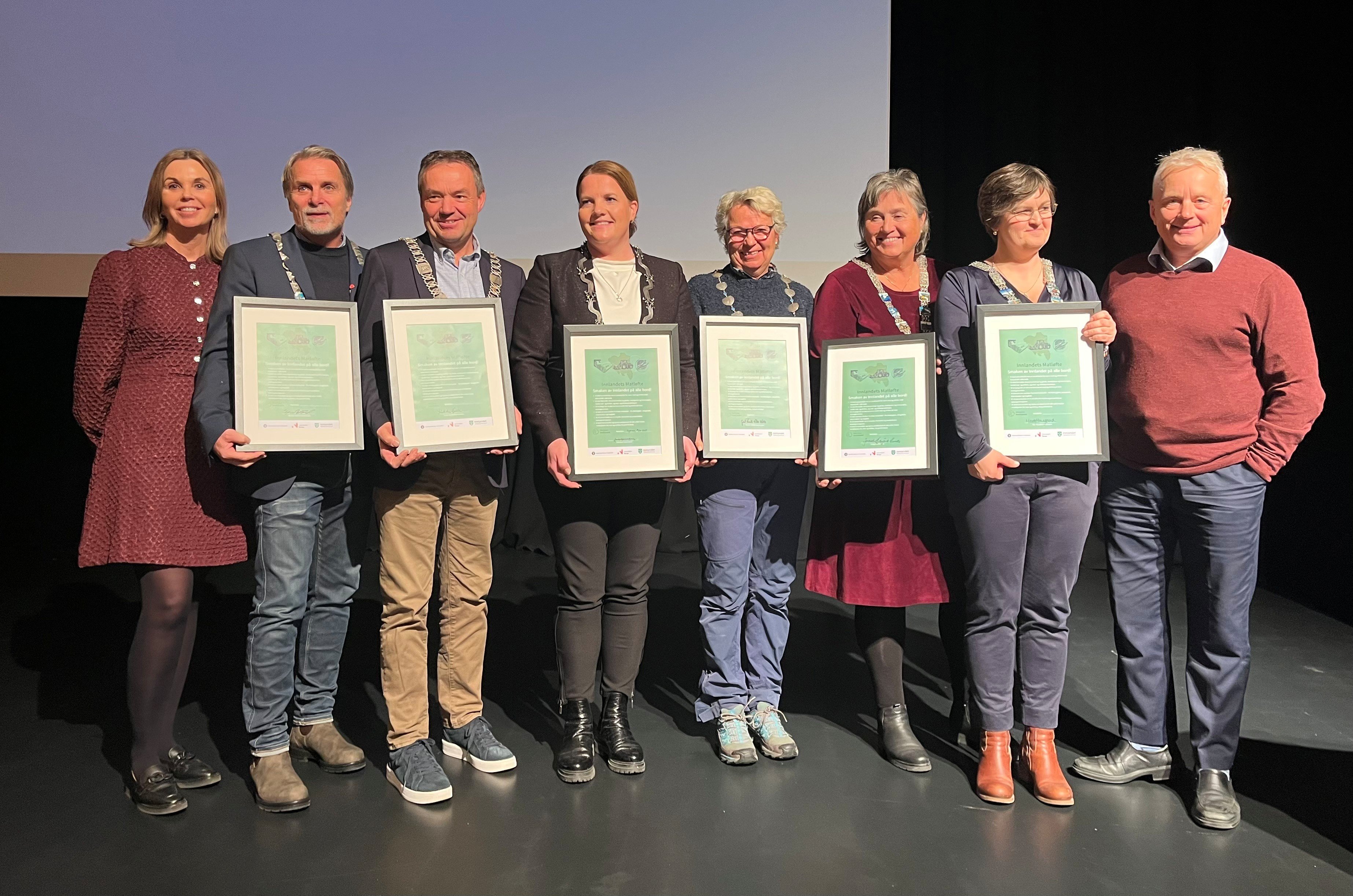 Åtte personer på rekke der seks er ordførere i Valdres som viser dokumentet de har signert. På yttersidene står statsforvalter Knut Storberget til høyre og seniorrådgiver Turid Windjusveen Olsen til venstre. 