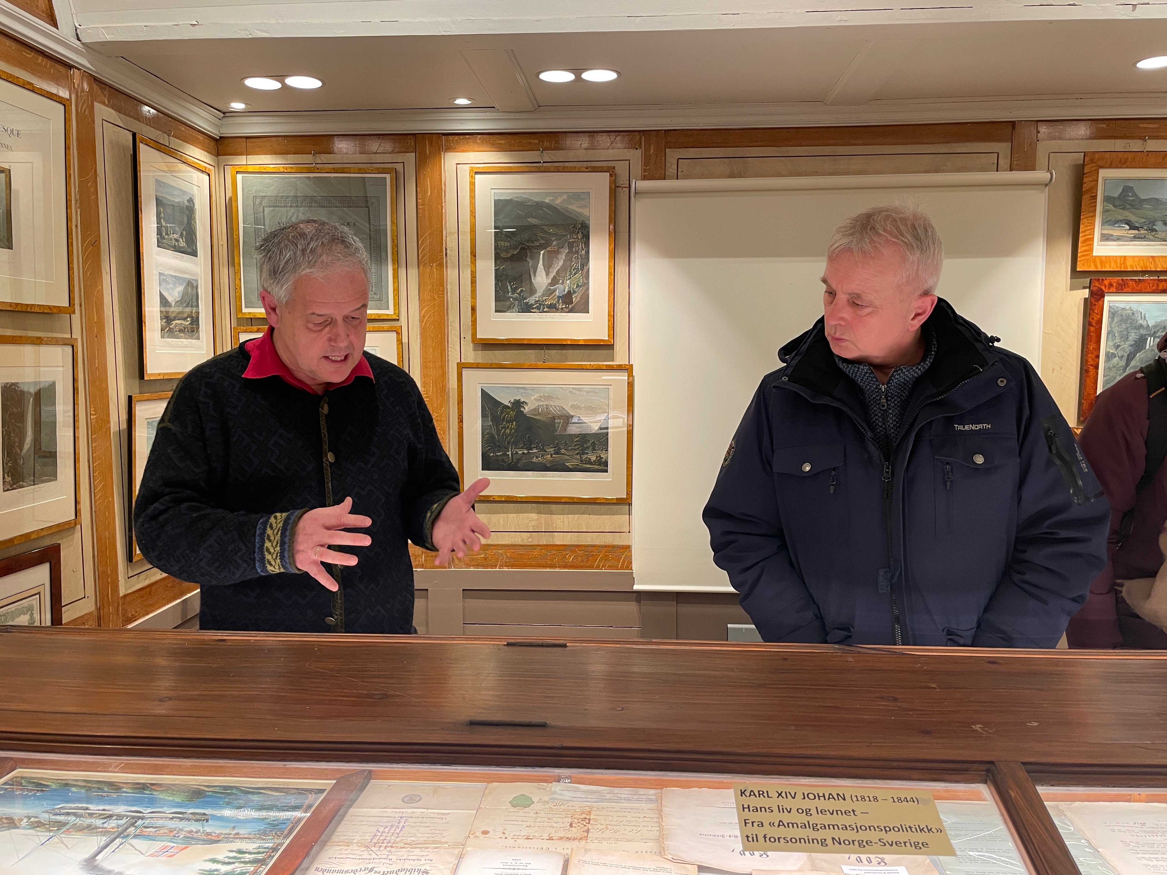 Statsforvalter Knut Storberget og Pål Sagen betrakter mange av de historiske skattene i museet. Foto: Aslak Nordstoga Lilleland. Folk ser i glassmonter