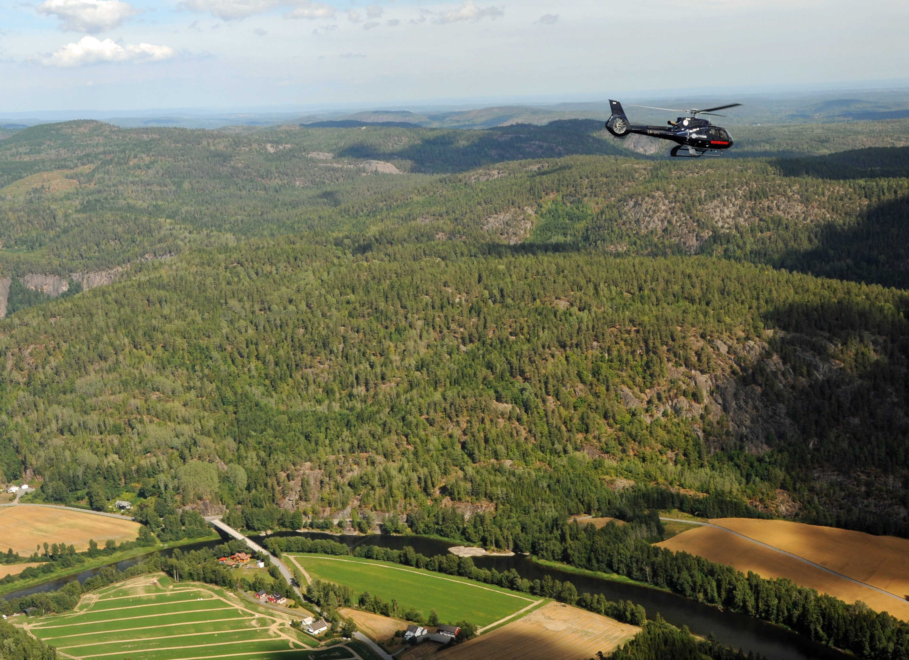 Foto: Morten Harangen / DSB. Bildet viser et skogbrannhelikopter som svever over skogen.