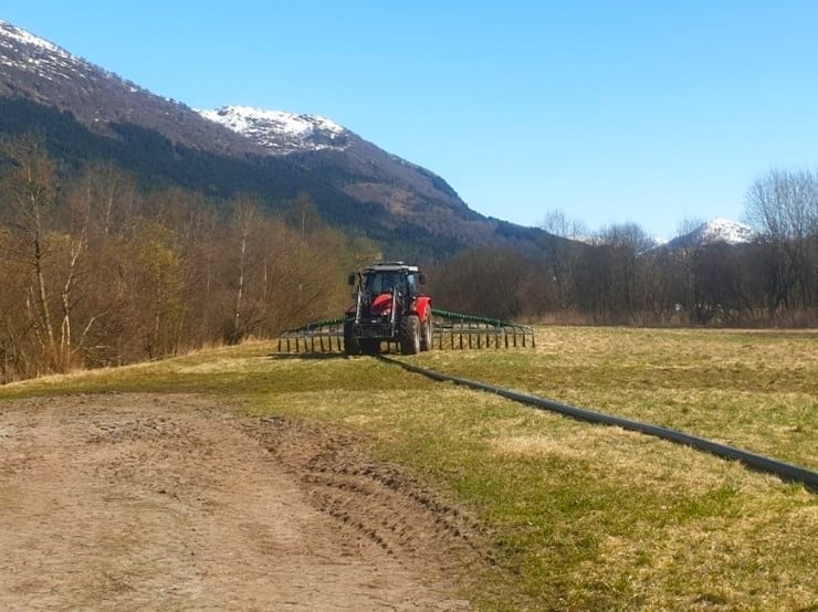 Bilde av en Traktor med slepeslange og nedleggingsutstyr.
